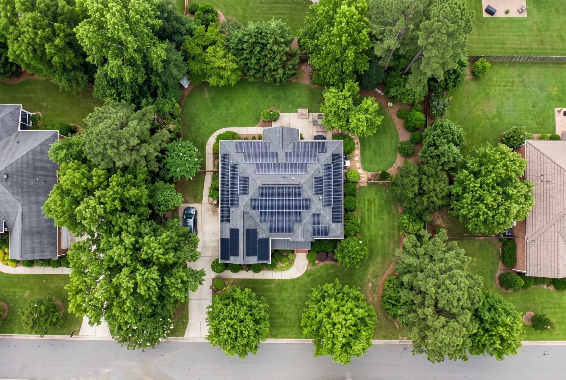 An aerial view looking down at a suburban roof fully covered with a solar array.